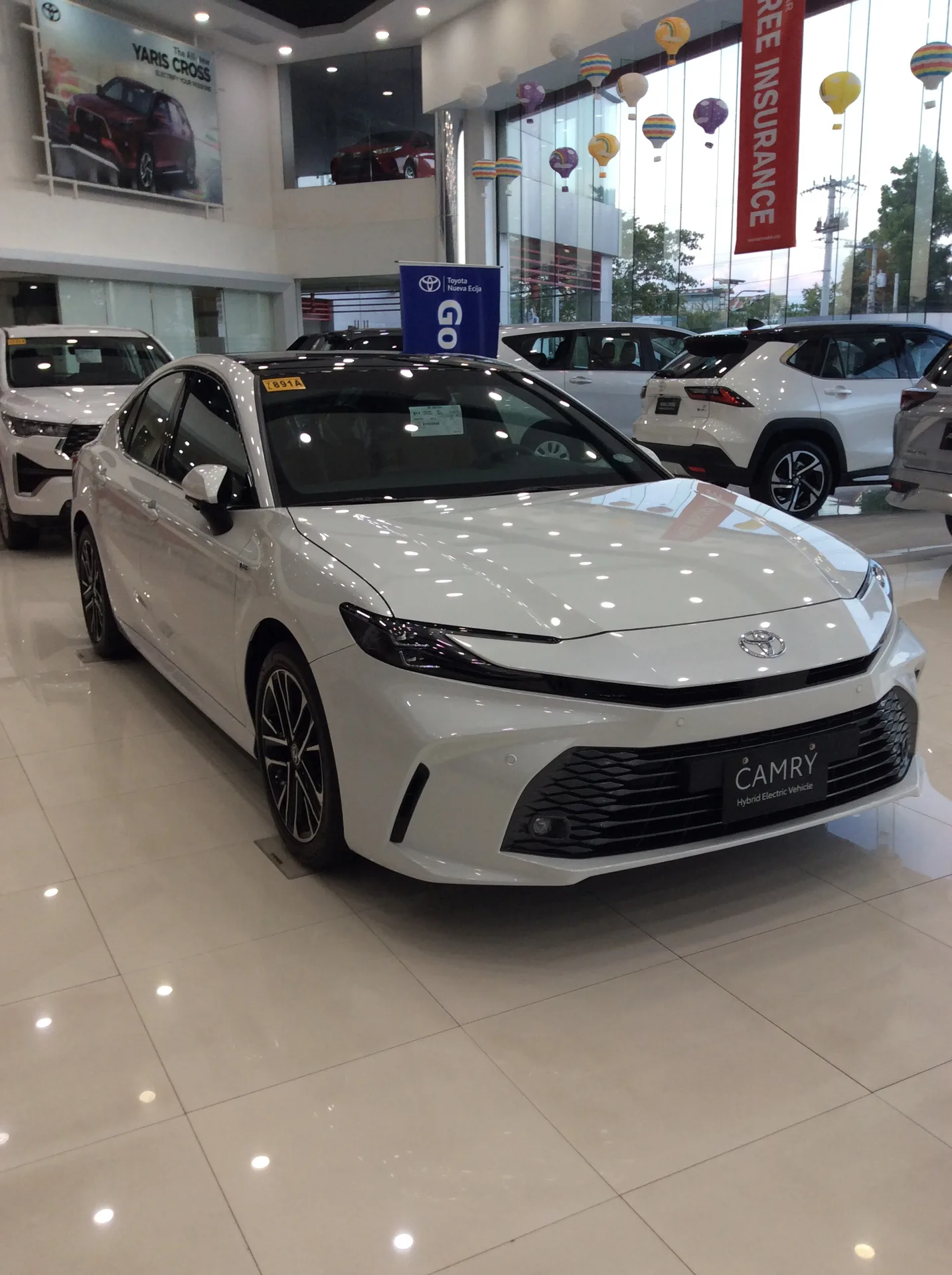 White current-generation Toyota Camry shown from the front left in portrait orientation